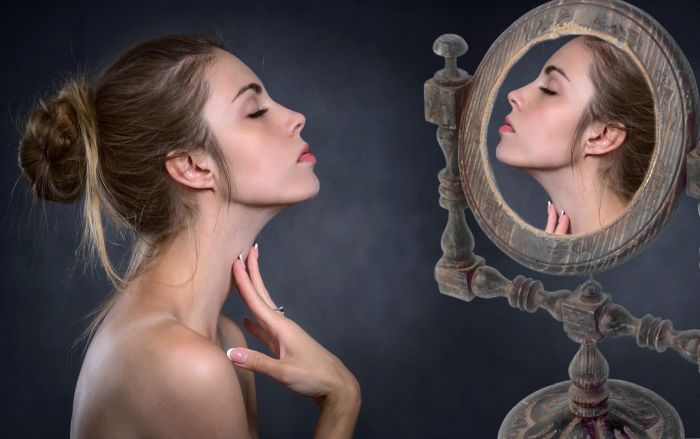 Femeie fără riduri care se privește în oglindă